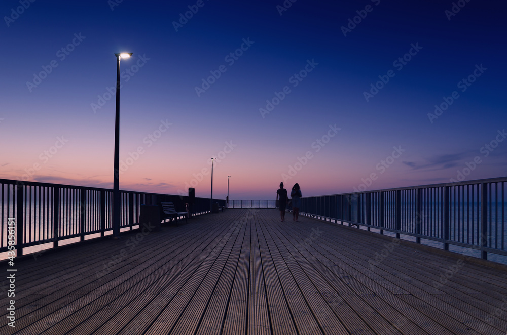 PIER ON THE SEA COAST - Womens walk at a quiet sunset