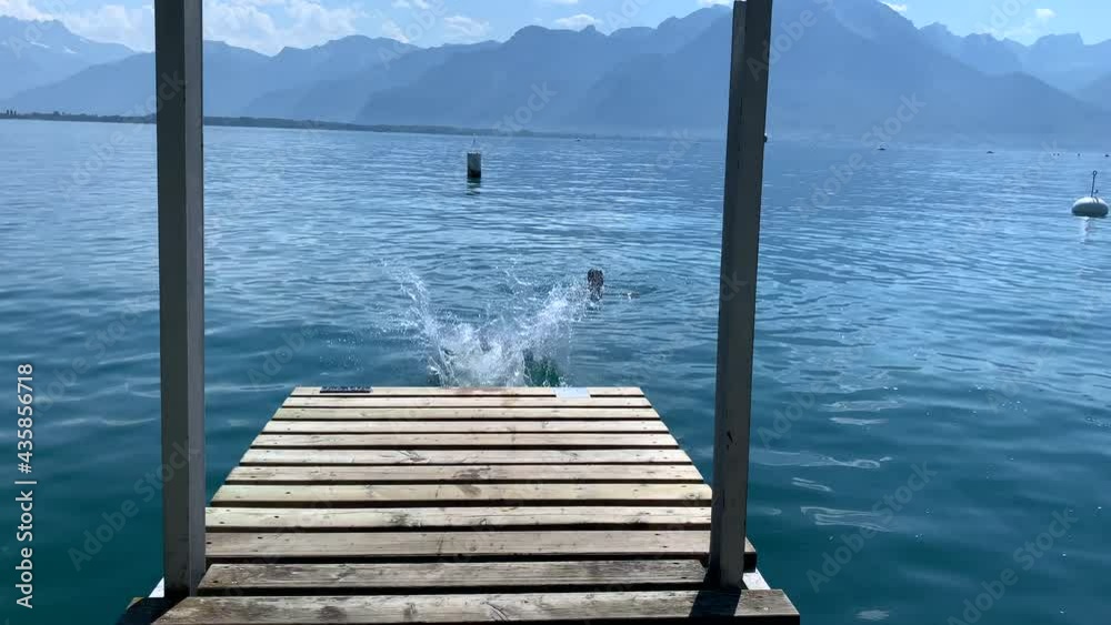 Young boy running by lake pier and jumping into water. child runs at pier and dives into lake