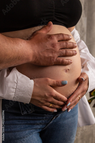 Hands of parents on a pregnant belly of a girl close up
