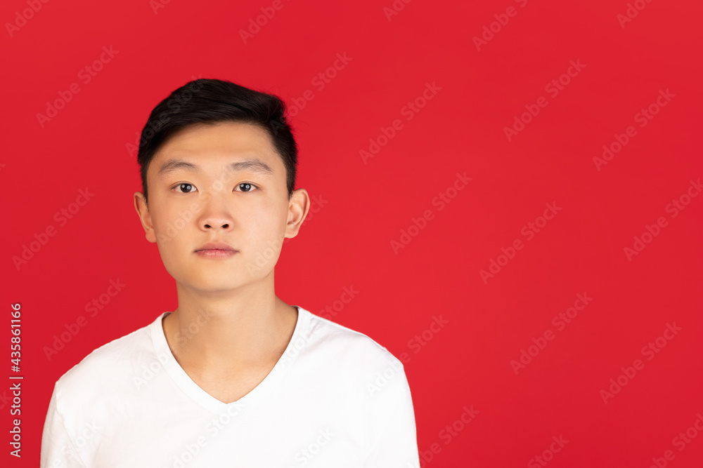 Asian young man's portrait on red studio background. Concept of human emotions, facial expression, youth, sales, ad. Asian young man's portrait on red studio background. Concept of human emotions, facial expression, youth, sales, ad.