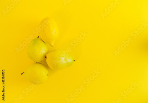 Neon yellow color trend. Minimalist depiction of summer fruit. Monochromatic fruit color. Yellow pears and lemon on an illuminate background as a symbol of the coming summer. Self - care.