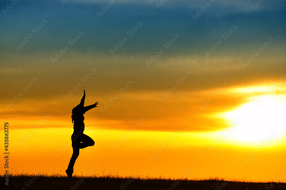 Silhouette of girl jumping in sunset.