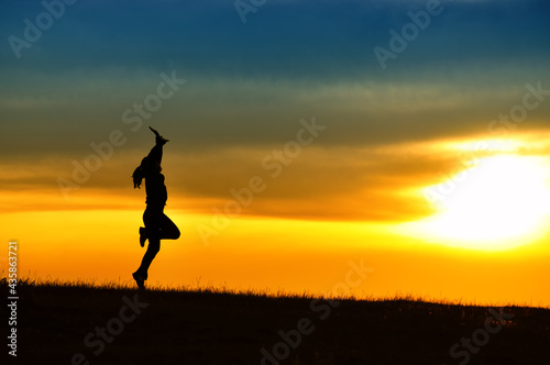 Silhouette of girl jumping in sunset. © Mihai