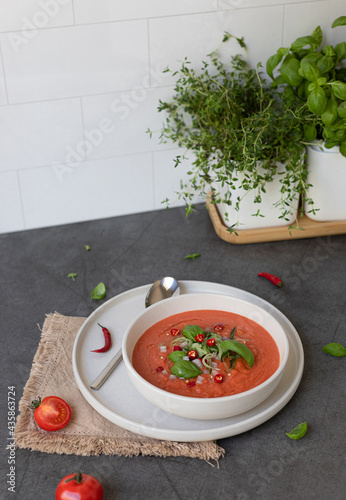 Gazpacho tomato soup with basil served in whitr bowl on dark grey background photo