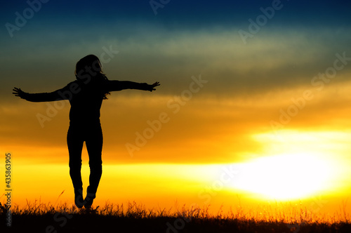 Silhouette of girl jumping in sunset.