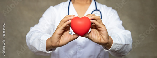 Professional doctor holding red heart shape in sideways. Health-care and medical in at hospital examination room. Heart attack disease concept. donate and pay for life