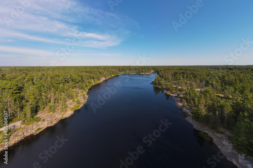 Aerial panorama of a fresh water lake surrounded by rugged rocky cliffs and endless green boreal coniferous forest. Northern Ontario  Canada.