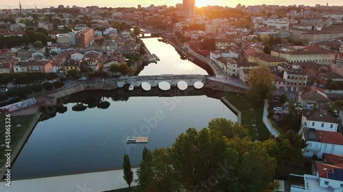 rimini city aerial shot at sunrise,drone flying over historic roman tiberius or tiberio bridge towards the sea photo