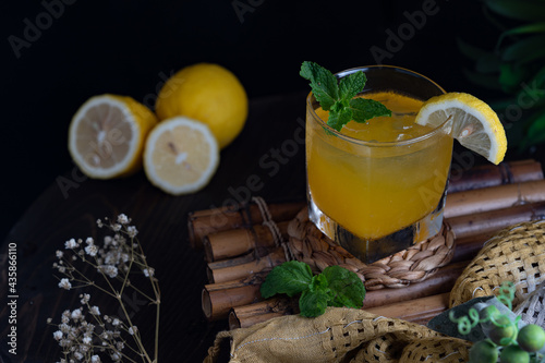 A glass of orange juice and decorated with three pieces of orange, mint leaves, cloth, other accessories.