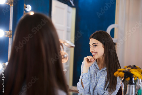Beautiful woman looking at herself in the mirror in a beauty salon