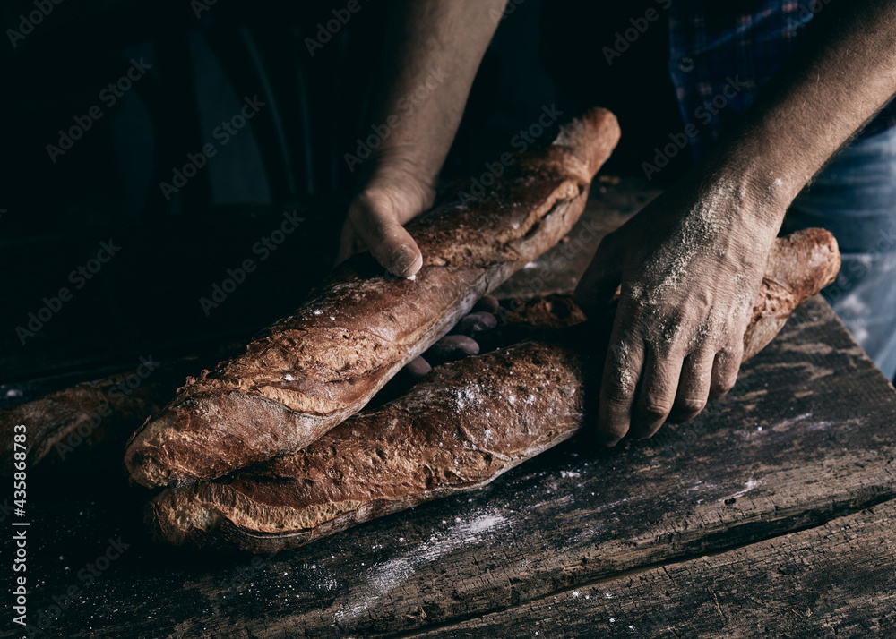 Crop baker putting rye baguettes on table
