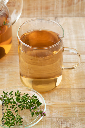 Glass cup of thyme tea and fresh thyme