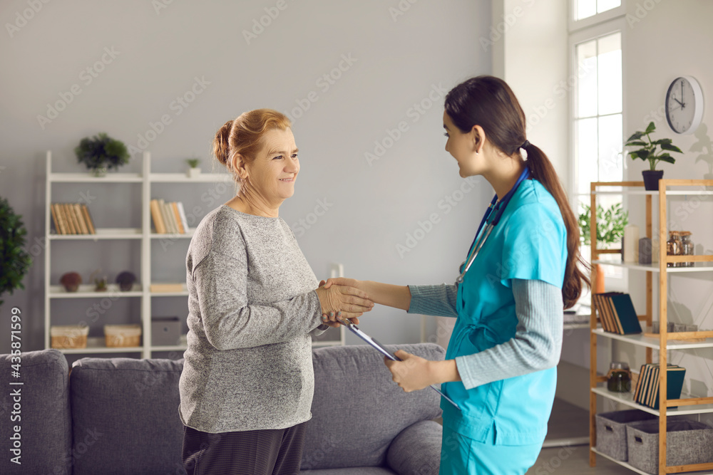 Obraz premium Professional medical consultation and health care for elderly people. Smiling friendly female doctor nurse greeting handshake senior old lady patient. Home appointment for old person