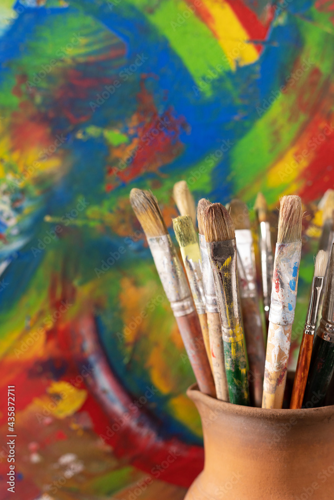 Paint brush in clay jug and oil painting  background texture. Paintbrush painting and art still life