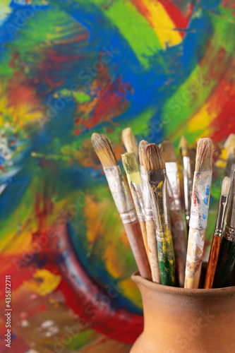 Paint brush in clay jug and oil painting background texture. Paintbrush painting and art still life