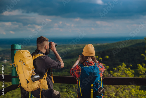 Couple of young hikers taking photo with a smartphone and looking into nature
