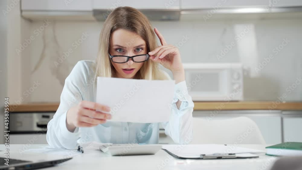 young female housewife sitting a table in house kitchen an incomprehensible deal with paperwork bills and loans. Woman is exhausted and frustrated with documents of enterprise or family budget at home young female housewife sitting a table in house kitchen an incomprehensible deal with paperwork bills and loans. Woman is exhausted and frustrated with documents of enterprise or family budget at home