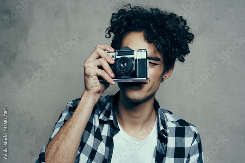 guy with a camera in his hands on a gray background indoors hobby plaid shirt model