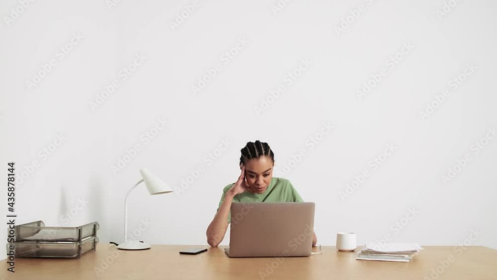 A thinking african american woman is using her laptop computer sitting in the office A thinking african american woman is using her laptop computer sitting in the office
