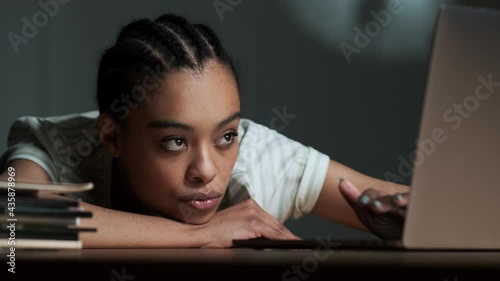 A bored american woman is using her laptop sitting in the office
