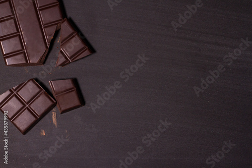 Broken pieces of chocolate and cocoa powder on wooden background