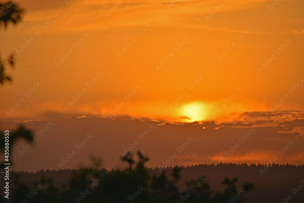 Fototapeta premium Sunset sun on the horizon with clouds in the evening