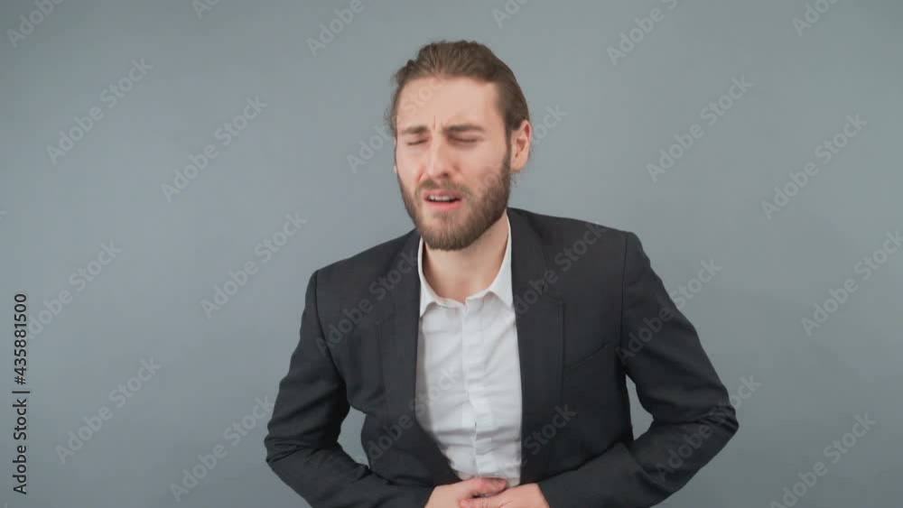 Young handsome businessman wearing suit and tie standing over isolated yellow background with hand on stomach because indigestion, painful illness feeling unwell. Ache concept. Young handsome businessman wearing suit and tie standing over isolated yellow background with hand on stomach because indigestion, painful illness feeling unwell. Ache concept.
