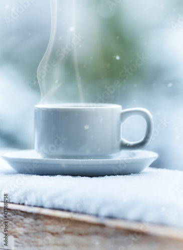 white coffee cup on a wooden table covered by snow