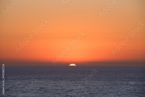 Sunset over the ocean horizon with bright orange sky