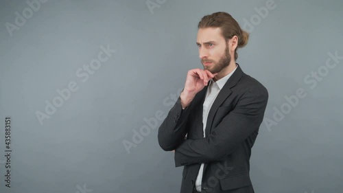 portrait of thinking business man touching chin isolated on gray background photo