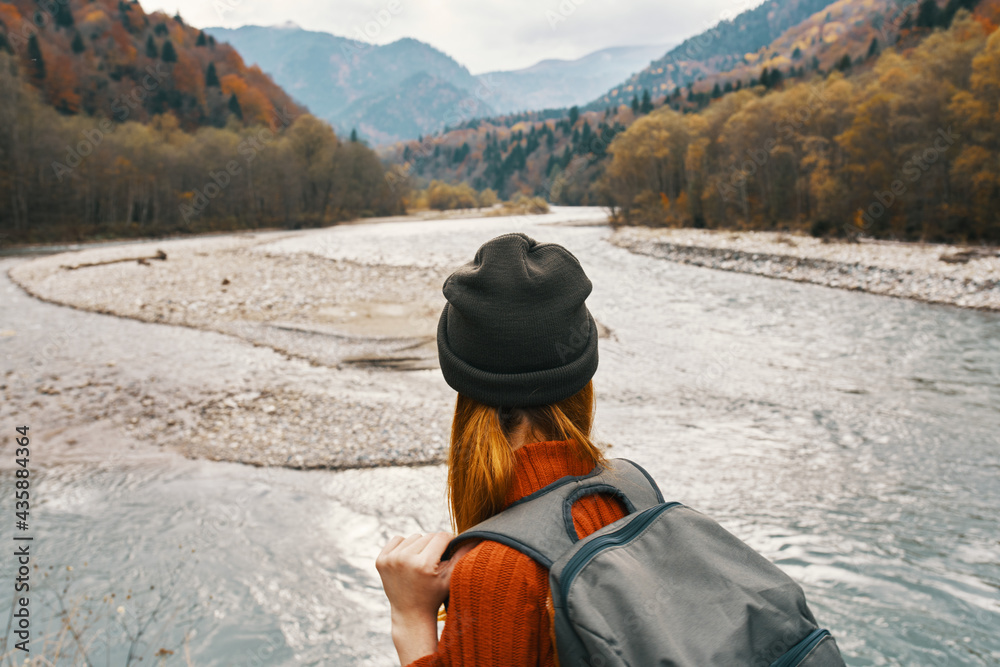 woman in a sweater and cap with a backpack on her back in the mountains on nature landscape woman in a sweater and cap with a backpack on her back in the mountains on nature landscape