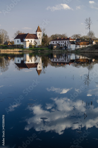 Alsunga catholic church and reflection in lake, Latvia. 