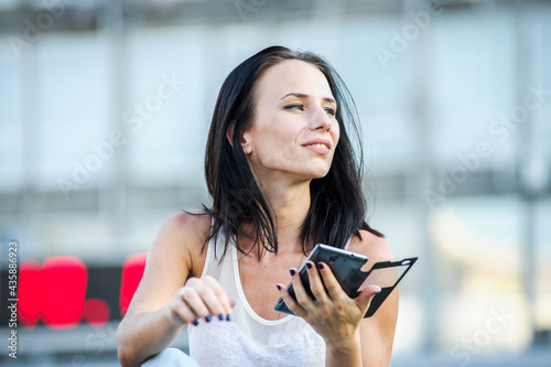 Yang and beautiful modern business woman poses outdoor with smart phone