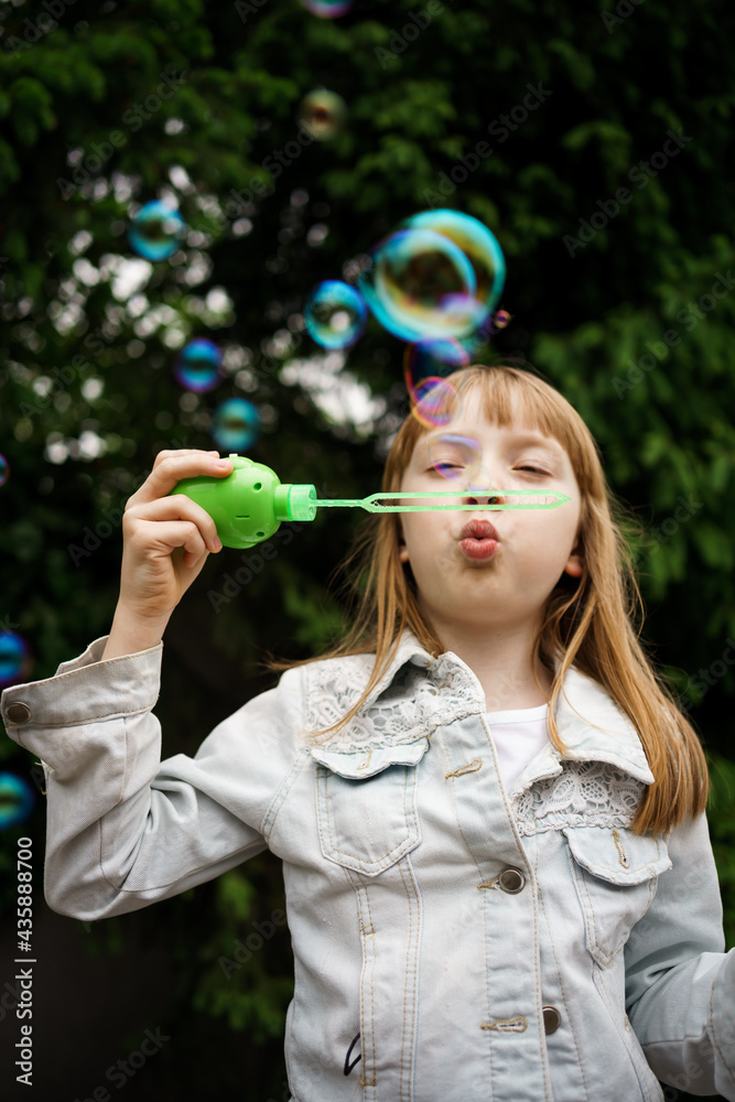 girl in a white denim jacket blowing soap bubbles girl in a white denim jacket blowing soap bubbles