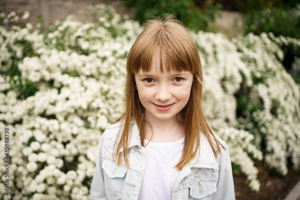 smiling girl in a white denim jacket near a flowering white bush smiling girl in a white denim jacket near a flowering white bush