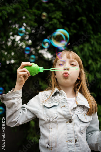 girl in a white denim jacket blowing soap bubbles