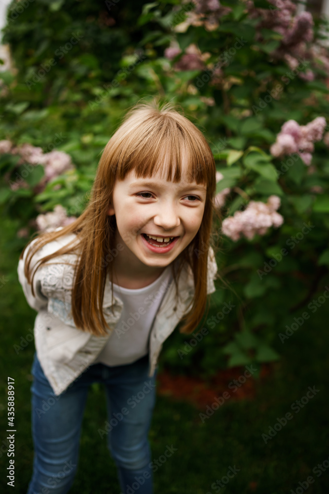 smiling girl in a white denim jacket near a bush of blooming lilacs smiling girl in a white denim jacket near a bush of blooming lilacs