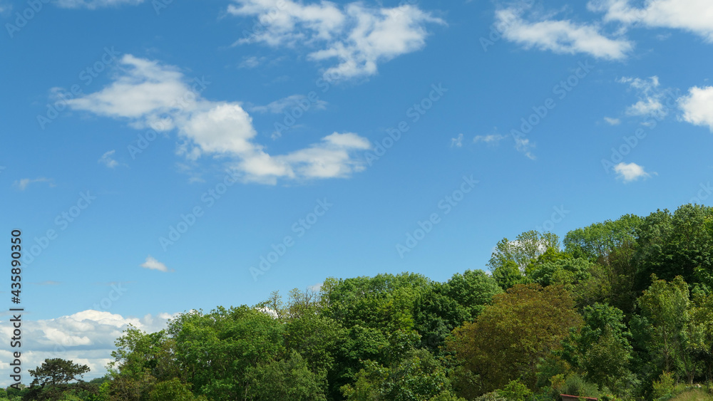 White clouds over a forest. Cumulonimbus in a blue sky over a hill at countryside.
