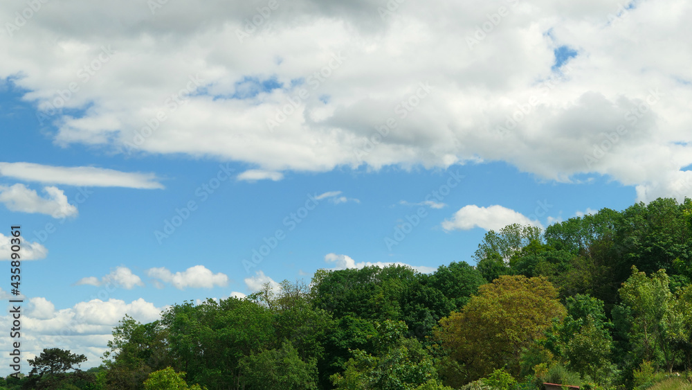 White clouds over a forest. Cumulonimbus in a blue sky over a hill at countryside.