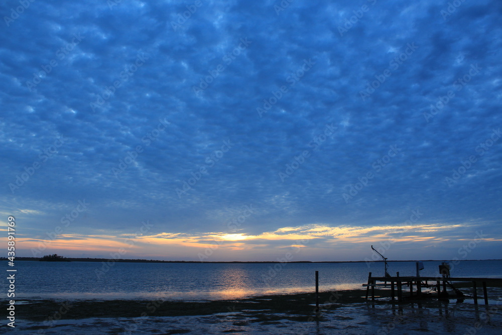 Dark clouds with glowing sky at sunset with a boat dock