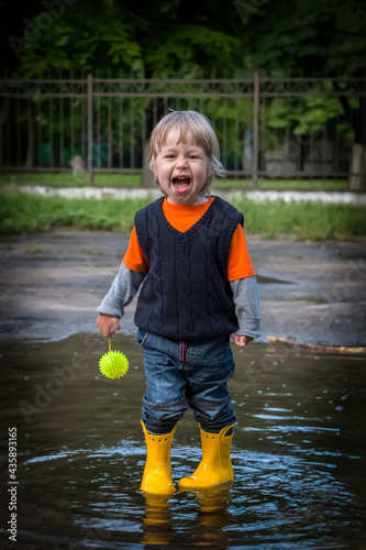 A joyful kid stands in a puddle.
