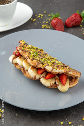 sandwich waffles with banana, strawberry and chocolate and pistachio on top