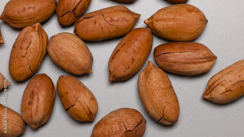 Pecan nuts in a hard shell with cracks on a gray background with a copy space. Top view or flat lay Pecan nuts in a hard shell with cracks on a gray background with a copy space. Top view or flat lay