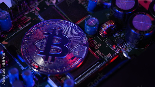 Bitcoin and semiconductor. Represent mining in Cryptocurrency cause global warming. Bitcoins on CPU board. Close-up Bitcoin with blue and pink light. circuit board with coin. Online asset concept. 