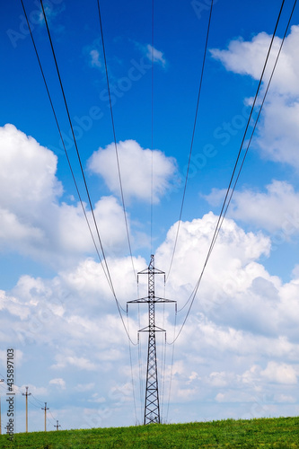 High voltage power lines and cloudy blue sky.