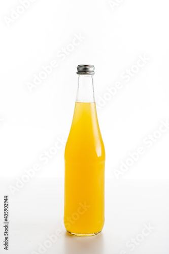 glass bottle of orange lemonade on a white background