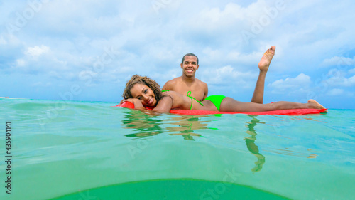 Couple at the beach playing, in the water with a float, interracial, black