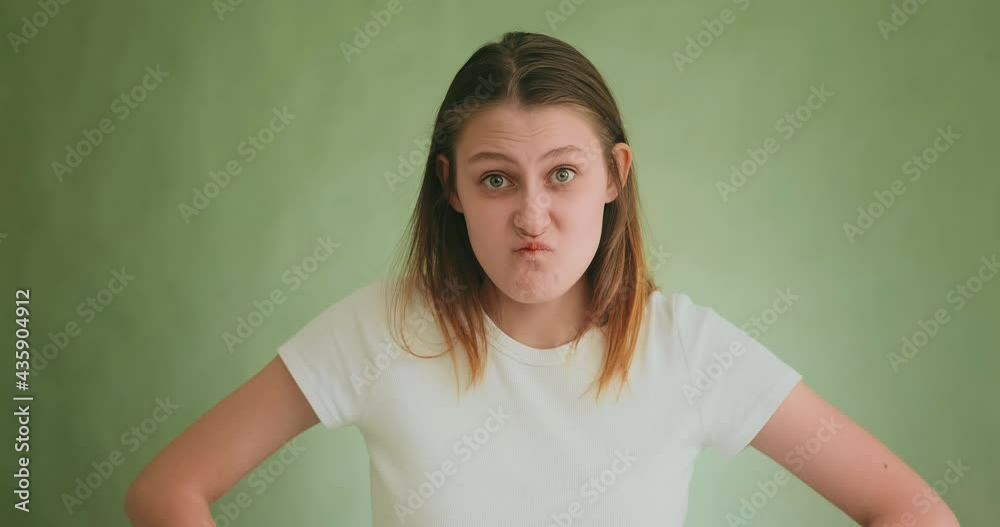 Funny lady in white clothes makes angry grimaces on green