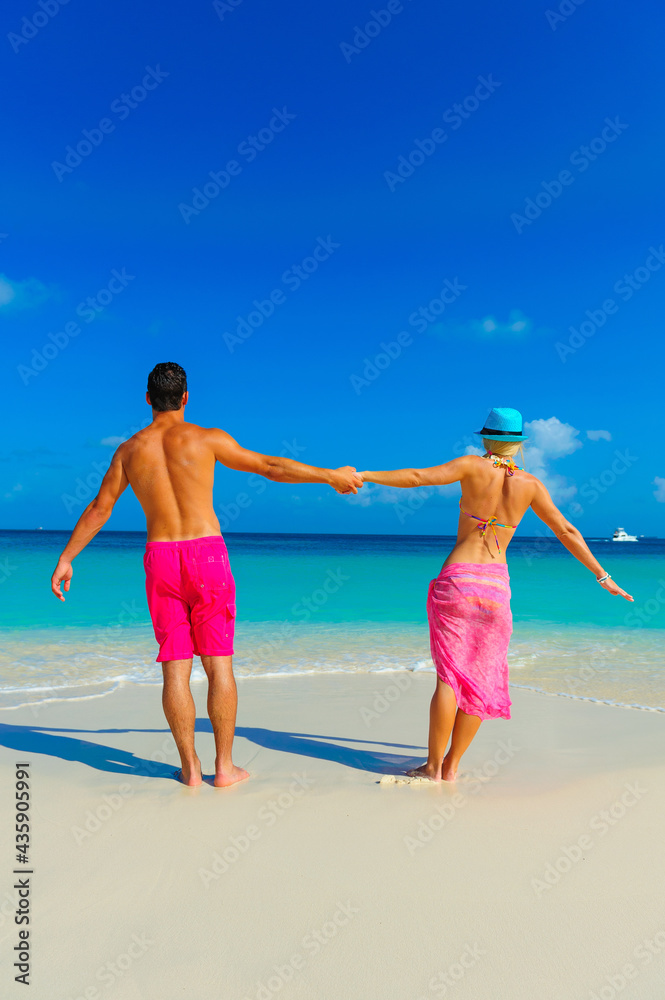 Couple at the beach, standng on the beach with pink outfits Couple at the beach, standng on the beach with pink outfits