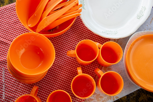 Clean orange reusable plastic tablewear on table with textile photo